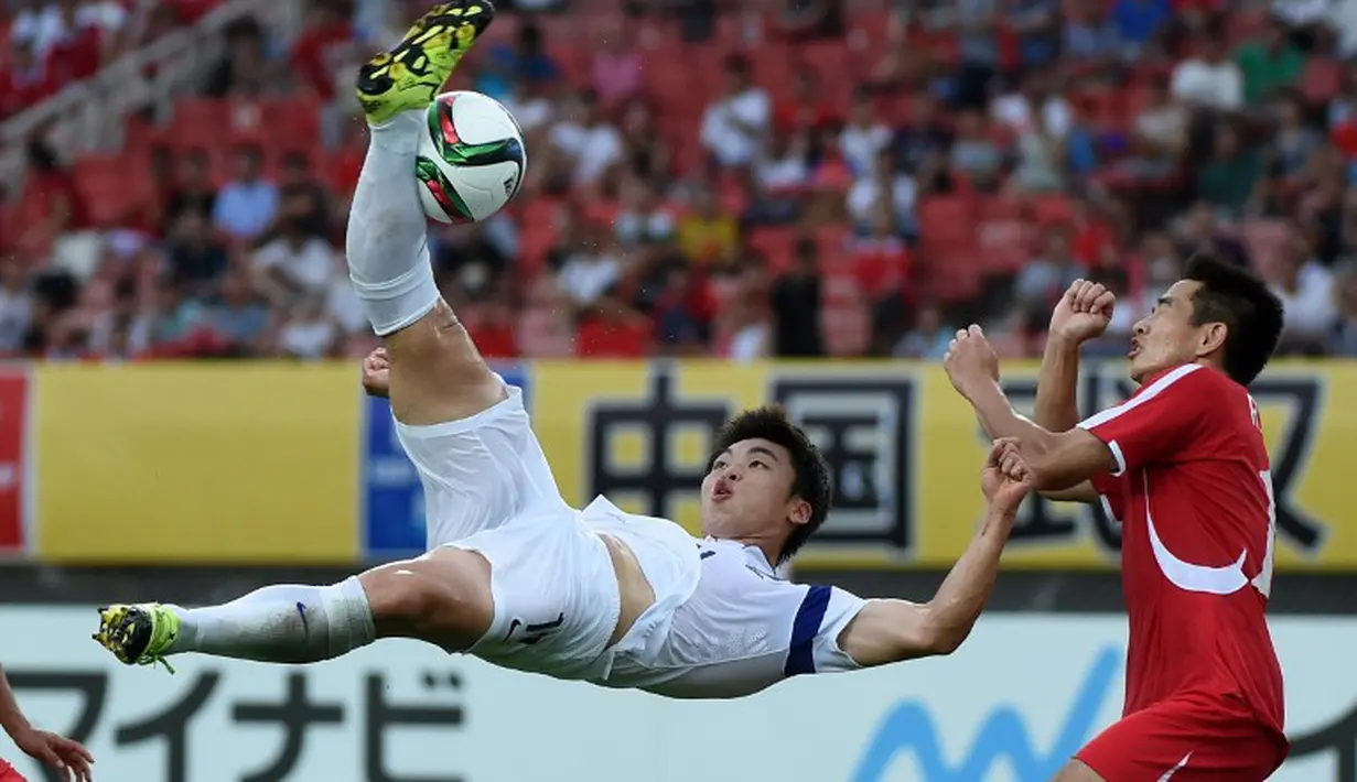Pemain Korea Selatan, Lee Jongho (kiri) mencetak gol dengan tendangan salto ke gawang Korea Utara dalam Turnamen Piala Asia Timur di Stadion Wuhan Sports Center, Wuhan, Tiongkok. (9/8/2015). (AFP Photo/Wang Zhao)