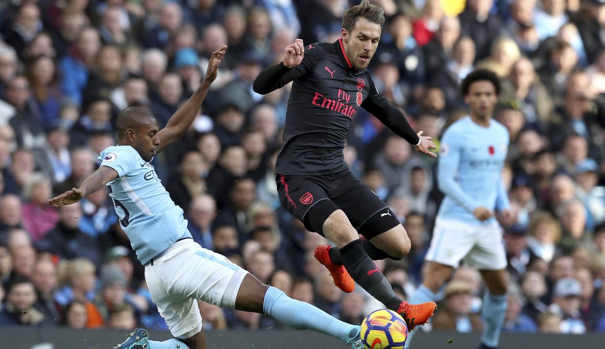 Gelandang Arsenal, Aaron Ramsey, berusaha melewati gelandang Manchester City, Fernandinho, pada laga Premier League di Stadion Ettihad, Manchester, Minggu (5/11/2017). City menang 3-1 atas Arsenal. (AP/Martin Rickett)