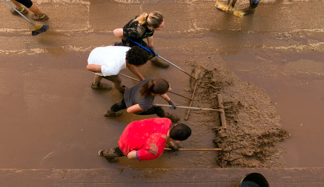 Warga membersihkan lumpur di jalan usai banjir bandang melanda daerahnya di Sant Llorenc, Mallorca, Spanyol (11/10). Banjir bandang tersebut telah menewaskan setidaknya 10 orang. (AP Photo/Francisco Ubilla)