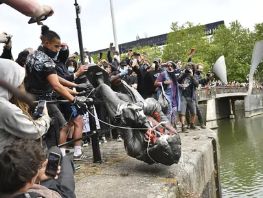 Demonstran melempar patung pedagang budak Edward Colston ke Pelabuhan Bristol saat protes Black Lives Matter di Bristol, Inggris, Minggu (7/6/2020). Aksi tersebut dilakukan sebagai bentuk protes atas kematian George Floyd saat ditangkap oleh polisi di Amerika Serikat. (Ben Birchall/PA via AP)
