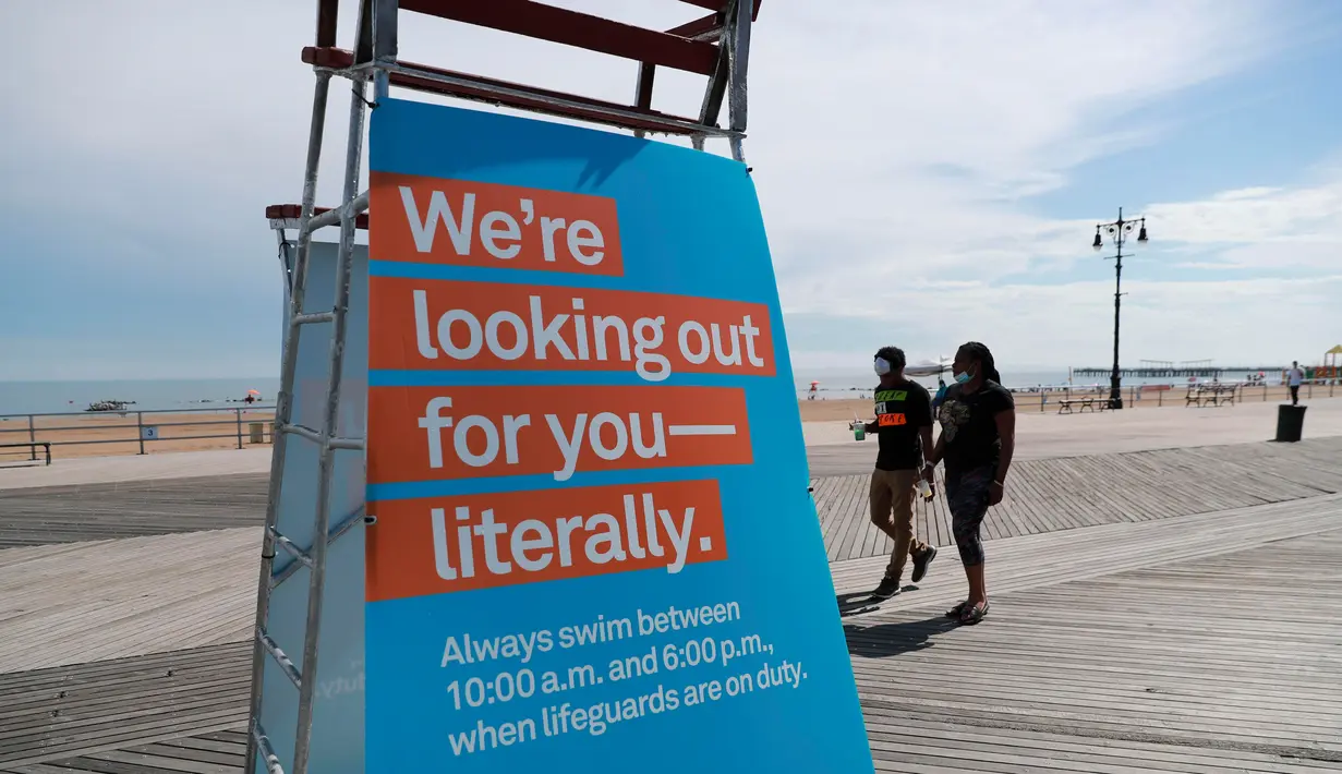 Sejumlah orang melewati papan pemberitahuan jam berenang di sebuah pantai di Coney Island, New York City, 1 Juli 2020. Pada Rabu (1/7), delapan pantai di New York City secara resmi dibuka untuk berenang selama jam kerja harian penjaga pantai, yakni mulai pukul 10.00 hingga 18.00. (Xinhua/Wang Ying)