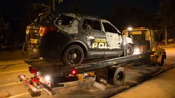 Mobil polisi Georgia berada di atas truk setelah dibakar pengunjuk rasa di depan kantor polisi di kampus di Atlanta, AS (18/9). Akibat kejadian ini dua petugas luka ringan, dengan satu dibawa ke rumah sakit untuk perawatan. (Foto AP / Kevin D. Liles)