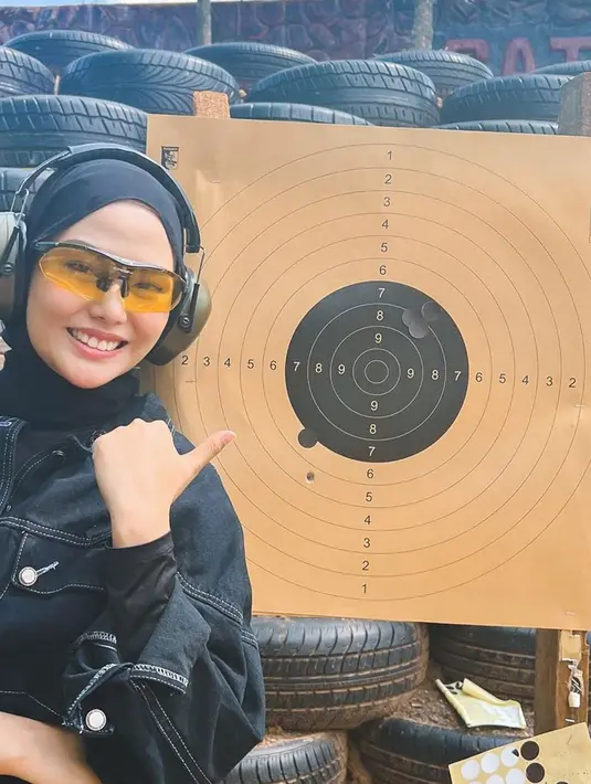 Dara Arafah tersenyum sumringah saat mempamerkan hasil bidikan tembakannya yang lumayan tepat sasaran. Dara terus mengevaluasi tembakannya agar benar-benar tepat di area incaran agar mendapatkan poin yang banyak. Kecantikan Dara saat tekuni hobinya ini ramai disebut netizen terlihat semakin memesona. (Liputan6.com/IG/@daraarafah)