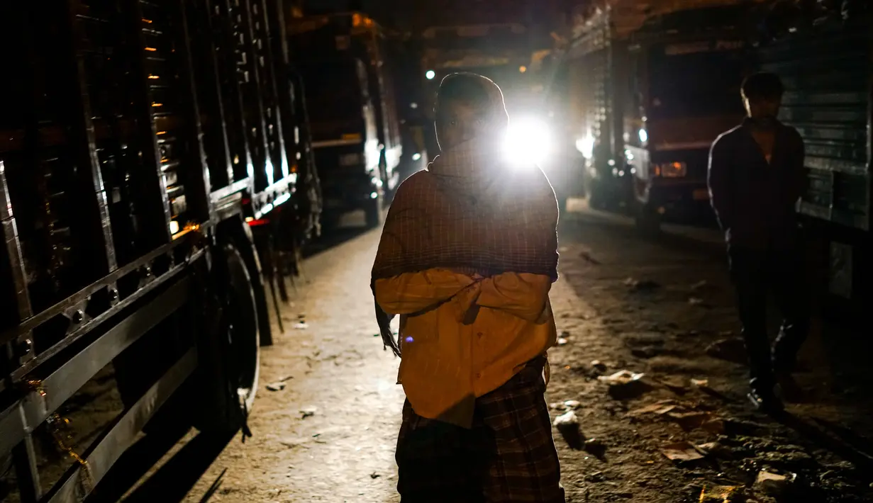 Seorang buruh berjalan di dekat truk yang terparkir di kawasan tua New Delhi, India (6/3). (AFP Photo/Chandan Khanna)