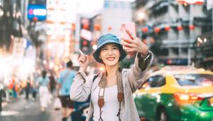 Wanita muda Asia yang sedang bepergian mengambil selfie dengan ponselnya. (depositphotos.com/dodotone)