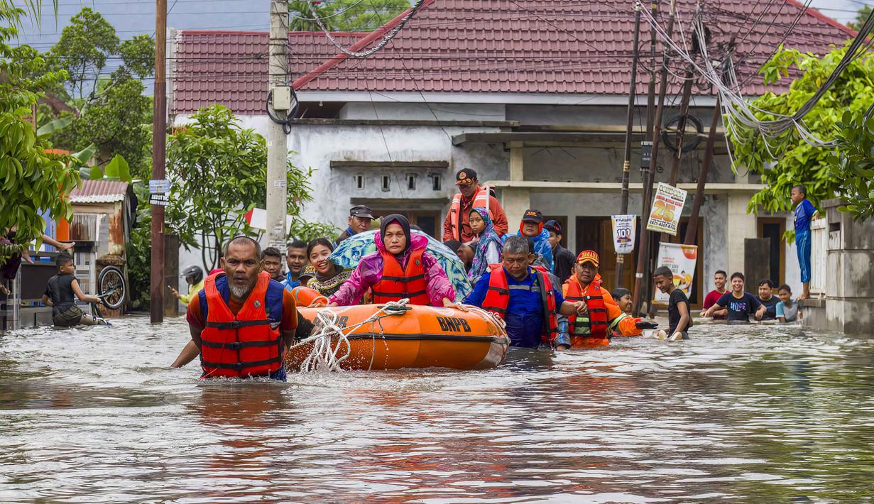 Selain berdampak pada warga, bencana hidrometeorologi yang terjadi ini juga menyebabkan kerusakan infrastruktur dan permukiman. Tampak dalam foto, tim penyelamat mengevakuasi perempuan dan anak-anak dengan perahu karet saat banjir melanda permukiman di Padang, Sumatra Barat, pada 25 November 2025. (Ade Yuandha/AFP)