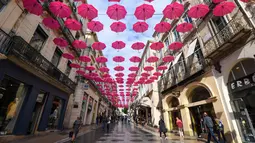 Pejalan kaki melintasi ratusan payung pink yang digantung sebagai tanda dukungan atas kewaspadaan bahaya kanker payudara di Montpellier, Prancis, Selasa (9/10). Bulan Oktober, ditetapkan sebagai bulan kewaspadaan atas kanker payudara. (AFP/PASCAL GUYOT)