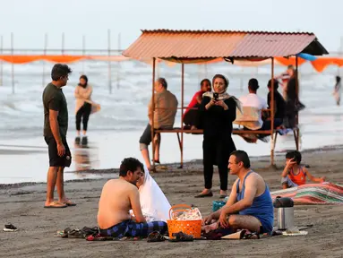 Warga Iran beristirahat sambil menikmati suasana di pantai di kota Laut Kaspia, Izadshahr, provinsi Mazandaran utara (8/7/2019). Laut Kaspia terletak di antara Eropa dan Asia, di sebelah barat dan barat-daya pegunungan Ural. (AFP Photo/Atta Kenare)