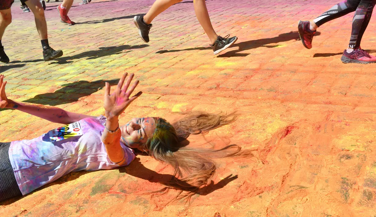 Seorang peserta terlentang sambil  disiram bubuk warna-warni saat mengikuti Kyiv Color Run di Kiev, Ukraina, Minggu (10/6). The Color Run diluncurkan dan diselenggarakan pertama kali pada Januari 2012 di Amerika Serikat. (AFP PHOTO/Sergei SUPINSKY)