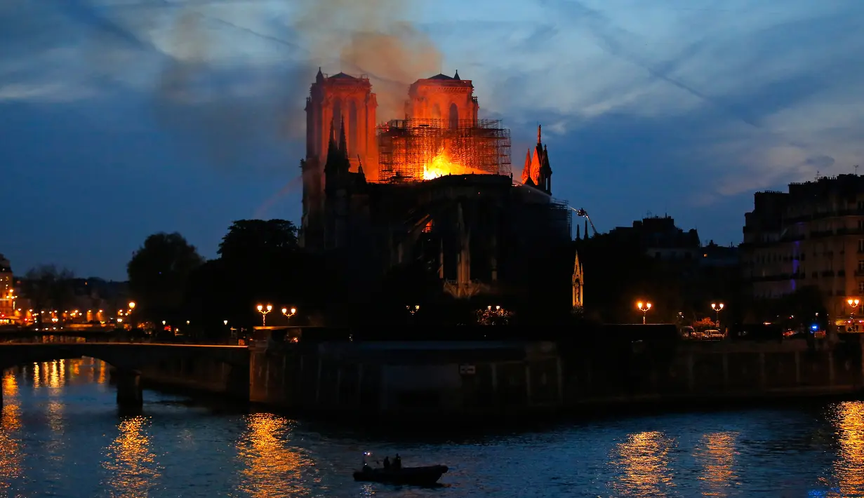 Petugas pemadam kebakaran berusaha memadamkan api dari Gereja Katedral Notre-Dame di kota Paris, Prancis, pada Senin (15/4). Tim pemadam kebakaran mengerahkan 400 anggota dari seluruh Prancis, termasuk menggunakan 18 selang bertekanan tinggi dan berjibaku selama berjam-jam. (AP Photo/Michel Euler)