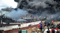 Sejumlah pekerja dan petugas pemadam kebakaran mencoba memadamkan api kapal nelayan di pelabuhan Benoa, Denpasar, Bali, Senin (9/7). Kebakaran yang menghanguskan puluhan kapal diperkirakan mencapai kerugian Rp 3 - 4 miliar. (AFP Foto / Sonny Tumbelaka)