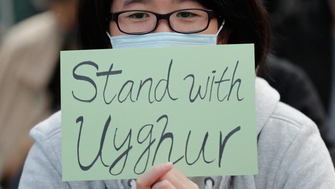 Seorang demonstran memegang kertas bertuliskan dukungan untuk Uighur dan perjuangan mereka terhadap hak azasi manusia di Hong Kong, Minggu (22/12/2019). Demonstran memprotes kebijakan China terkait minoritas Uighur. (AP Photo/Lee Jin-man)