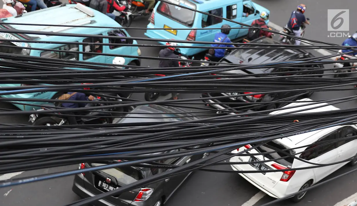 Instalasi kabel semrawut menjuntai di Jalan Dewi Sartika, Jakarta Timur, Sabtu (19/1). Selain mengganggu keindahan kota, kondisi tersebut juga berbahaya karena dapat memicu hubungan pendek arus listrik. (Liputan6.com/Immanuel Antonius)