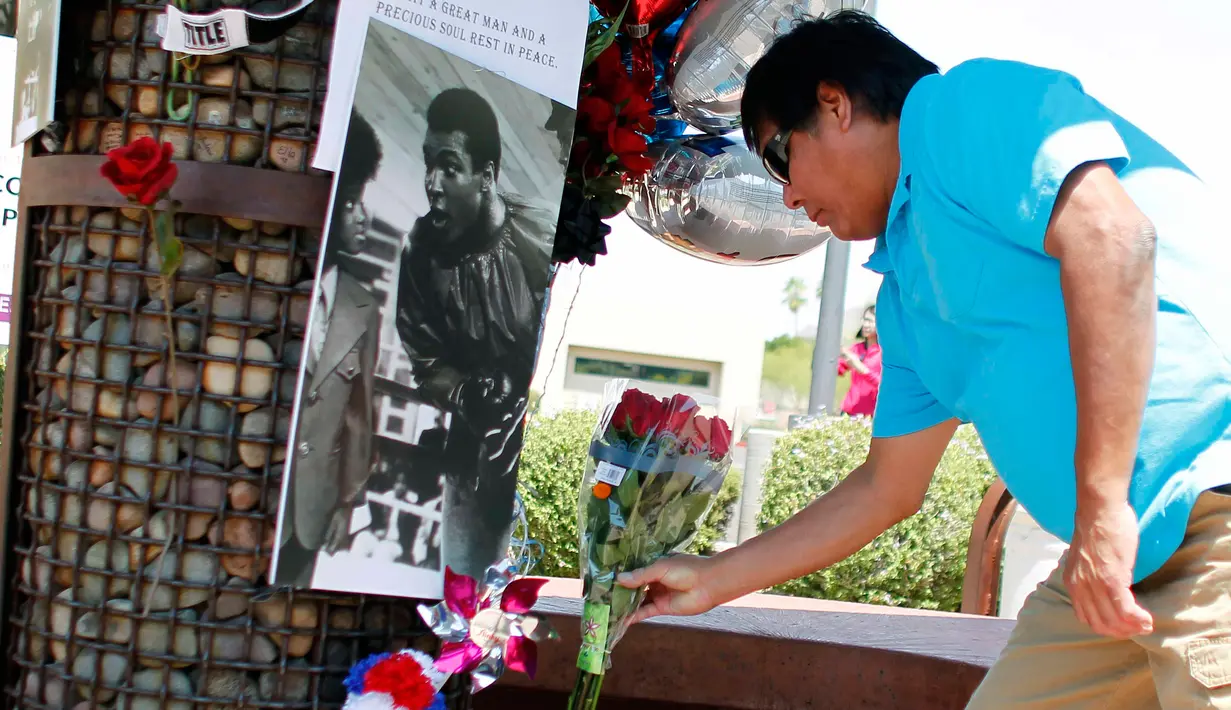 Seorang pria meletakkan karangan bunga di lokasi untuk mengenang kematian petinju legendaris Muhammad Ali, di Phoenix, Arizona, AS, Sabtu (4/6). Muhammad Ali meninggal pada usai 74 tahun setelah mendapatkan perawatan di RS. (REUTERS/Ricardo Arduengo)