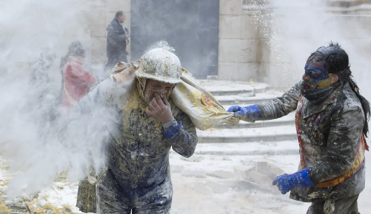 Peserta Festival Els Enfarinats saling menyerang dengan tepung dan telur, kota Ibi, Spanyol, Rabu (28/12). Perayaan Els Enfarinats digelar untuk memperingati Day of the Innocents. (AFP PHOTO / Jamie Reina)