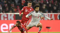 Aksi Mohammed Salah lewati Rafinha pada leg kedua, babak 16 besar Liga Champions yang berlangsung di Stadion Allianz Arena, Munchen, Kamis (14/3). Liverpool menang 3-1. (AFP/ Christof Stache)