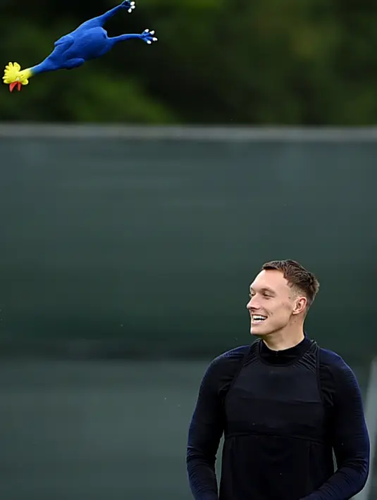 Bek Inggris, Phil Jones bersiap menangkap mainan ayam selama mengikuti sesi latihan tim di Repino, Rusia (10/7). Inggris akan bertanding melawan Kroasia pada babak semifinal Piala Dunia 2018. (AFP Photo/Ellis)