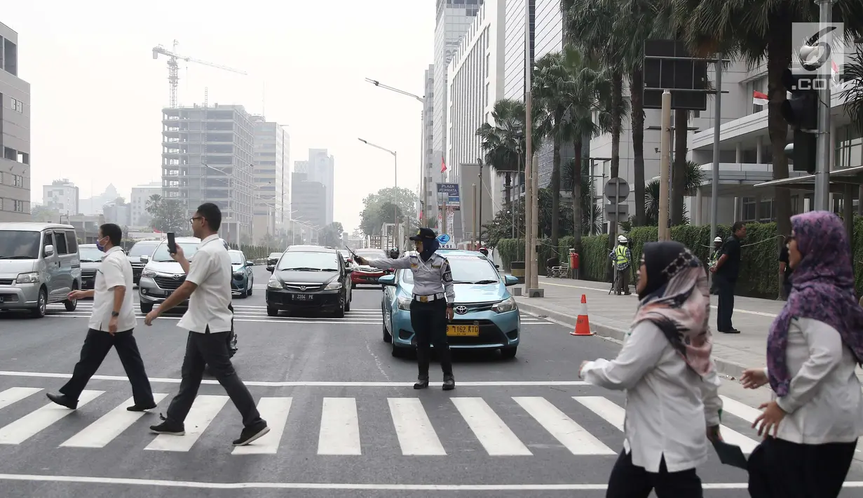 Petugas mengatur lalu lintas di pelican crossing di kawasan Thamrin, Jakarta, Minggu (29/7). Pelican crossing di kawasan Thamrin sudah bisa di gunakan pengganti JPO yang akan dibongkar. (Liputan6.com/Herman Zakharia)