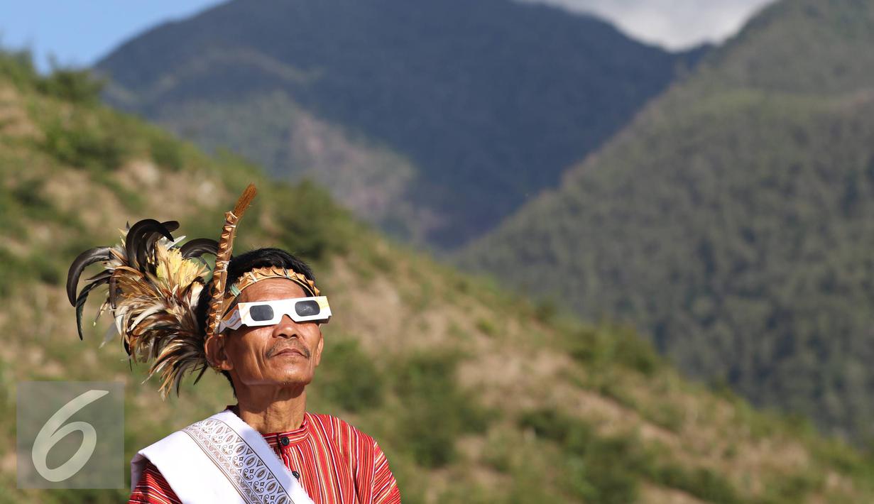 Seniman memakai kacamata melihat gerhana matahari di Bukit Matantimali, Sigi, Sulawesi Tengah, Rabu (9/3). Tarian tersebut dilakukan dalam rangka menyambut gerhana matahari total serta menolak bala. (Liputan6.com/Immanuel Antonius)