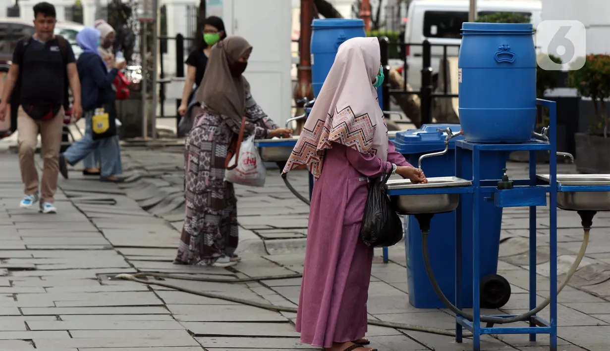 Pengunjung mencuci tangan sebelum memasuki kawasan Kota Tua Jakarta, Kamis (29/10/2020). Libur panjang di masa pemberlakuan PSBB transisi Jakarta dimanfaatkan warga untuk mengunjungi lokasi-lokasi wiisata. (Liputan6.com/Helmi Fithriansyah)