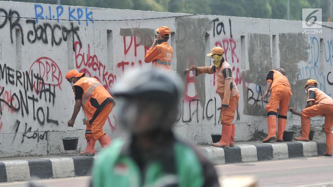 Petugas PPSU membersihkan coretan yang mengotori tembok di kawasan Gedung DPR, Jakarta, Rabu (25/9/2019). Demonstrasi mahasiswa yang berujung ricuh yang berujung kerusuhan tersebut menyebabkan fasilitas umum rusak dan penuh coretan yang dibuat oleh pendemo. (merdeka.com/Iqbal S Nugroho)