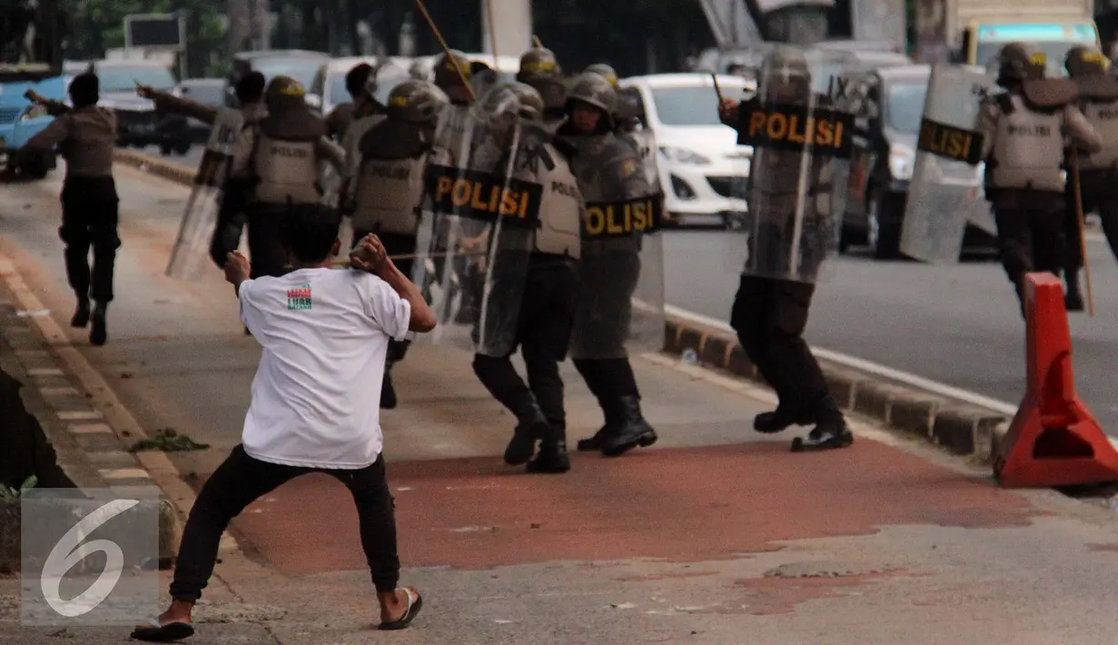 Massa melempari aparat Kepolisian dengan batu di depan kantor KPK, Jakarta, Jumat (20/5). Aksi menuntut KPK untuk segera mengusut keterlibatan Ahok di Sumber Waras ini berakhir ricuh. (Liputan6.com/Yoppy Renato)
