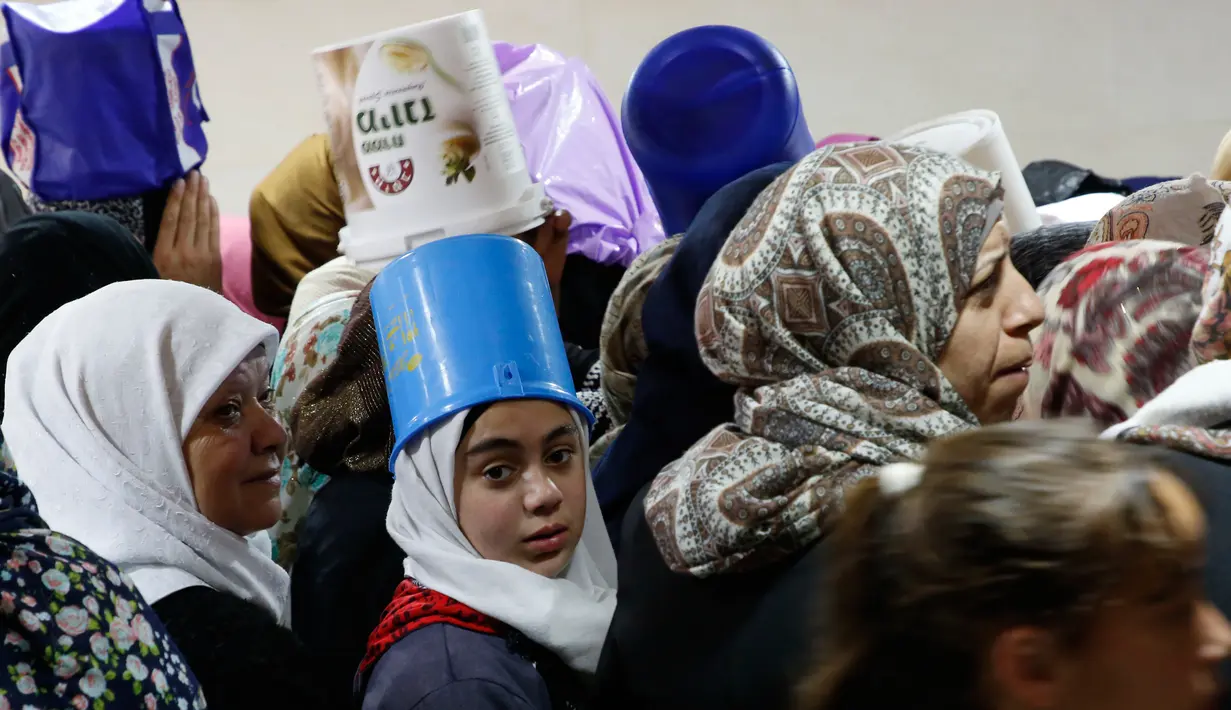 Anak-anak dan perempuan Palestina mengantre untuk makanan buka puasa gratis di dapur amal, Hebron, Tepi Barat, Minggu (20/5). Dapur amal yang dikelola Wakaf Islam itu dinilai sangat membantu dalam mencukupi gizi selama bulan Ramadan. (AFP/HAZEM BADER)