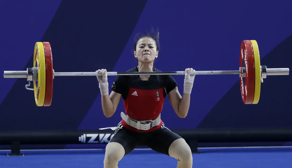 Lifter Windy Aisyah melakukan angkatan saat SEA Games 2019 cabang angkat besi nomor 49 kg di Stadion Rizal Memorial, Manila, Minggu (1/12). Dirinya meraih emas dengan total angkatan 104 kg. (Bola.com/M Iqbal Ichsan)