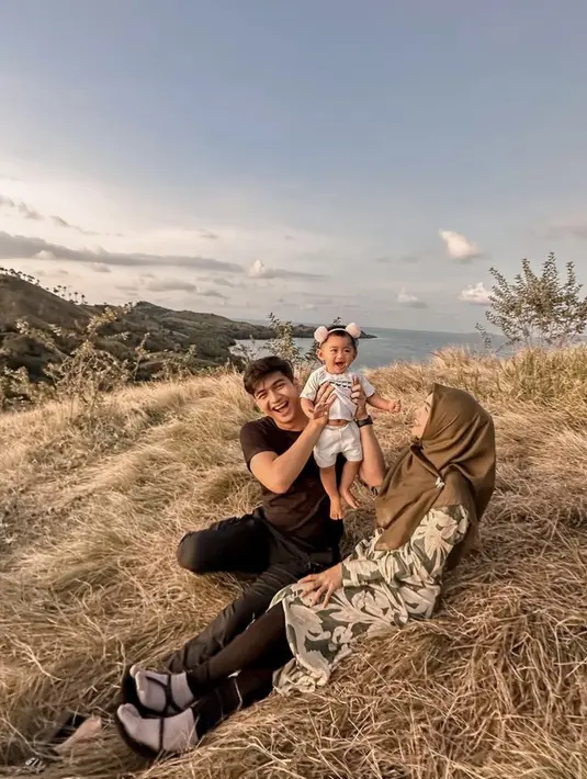 Ria Ricis bersama suami dan anaknya juga liburan ke Labuan Bajo. Ria Ricis tampil dengan dress bermotif bunga dipadukan kerudung cokelat. Credit: (@riaricis1795)