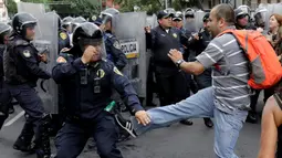 Seorang demonstran berusaha menendang petugas saat bentrok terjadi memprotes penentangan adu banteng di luar arena adu banteng di Mexico City, Meksiko 29 Mei 2016. (REUTERS / Henry Romero)