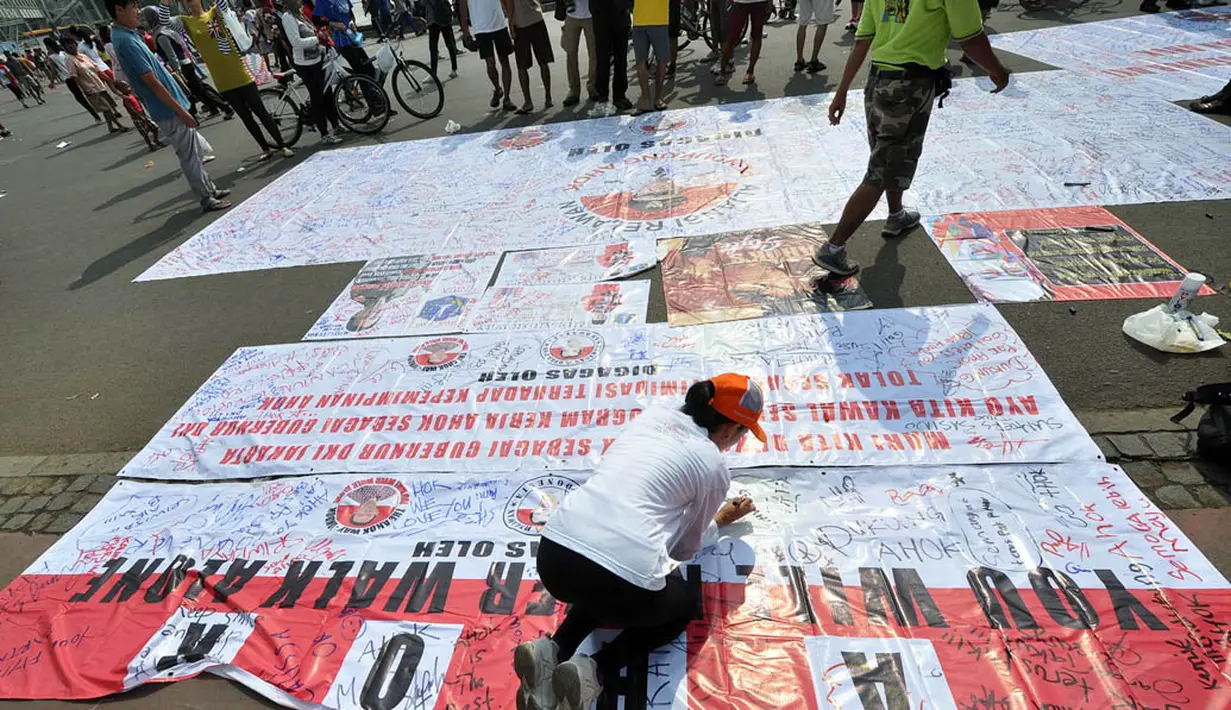 Seorang warga saat menandatangani spanduk sebagai bentuk dukungan kepada Ahok menjadi Gubernur DKI Jakarta. Foto diambil pada 9 November 2014. (Liputan6.com/Miftahul Hayat)