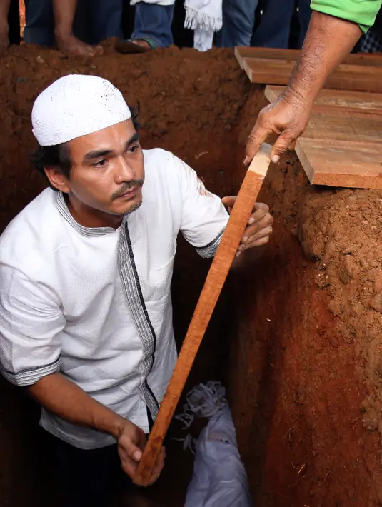 Sebagai bentuk penghormatan terakhir, sang menantu, Teddy Syach langsung turun ke liang lahat untuk membantu menurunkan jenazah. Teddy pula yang mengadzankan jenazah sebelum ditutup dengan tanah.  (Adrian Putra/Bintang.com)