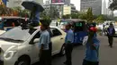 Sopir duduk diatas taksi membawa payung saat demo di depan Gedung DPR/MPR, Jakarta, Selasa (22/3). Selain melakukan demo, sopir taksi tersebut melakukan sweeping ke supir taksi yang beroperasi di dalam tol dan membakar ban. (Liputan6.com/Ahmad Romadoni)