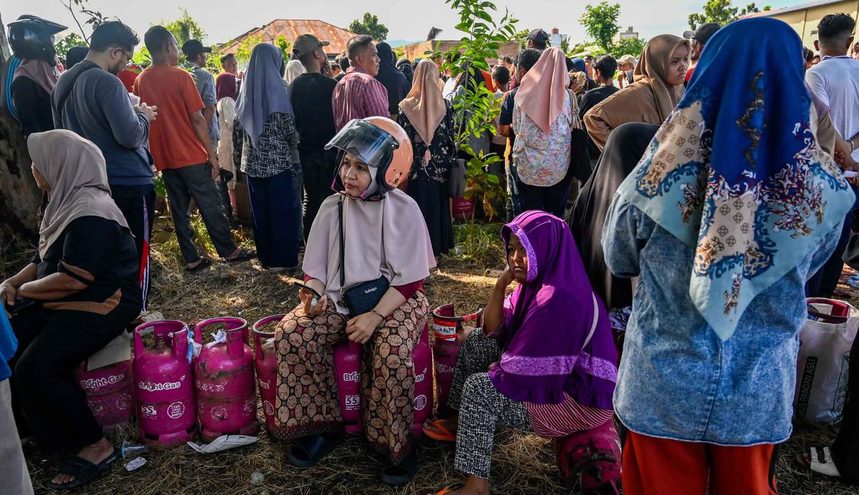 Kelangkaan gas di Kota Banda Aceh memicu kritik tajam dari berbagai pihak. Tampak dalam foto, warga menunggu untuk membeli tabung gas di sebuah stasiun pengisian dan pembelian LPG setelah banjir bandang di Banda Aceh pada Rabu 17 Desember 2025. (CHAIDEER MAHYUDDIN/AFP)