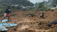 Foto selebaran yang diambil dan dirilis pada 6 Maret 2023 oleh BNPB (Badan Nasional Penanggulangan Bencana) ini menunjukkan orang-orang memeriksa kerusakan di sebuah desa yang dilanda tanah longsor di Natuna, Kepulauan Riau (Kepri) pada 6 Maret 2023.  (Photo by BNPB / AFP)