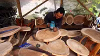 Hasyim, mengerjakan pembuatan furniture akar kayu. (Dhita/Liputan6.com)