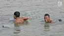 Anak-anak tertawa saat berenang di Danau Sunter, Jakarta, Selasa (23/7/2019). Anak-anak tetap nekat berenang di Danau Sunter kendati mereka sadar telah dilarang dan dapat membahayakan diri sendiri. (merdeka.com/Iqbal Nugroho)