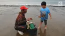 Pencari ikan menunjukkan hasil tangkapannya kepada anak kecil di Pantai Palangpang, Ciletuh, Sukabumi, Jawa Barat, Minggu (22/9). (Merdeka.com/Arie Basuki)