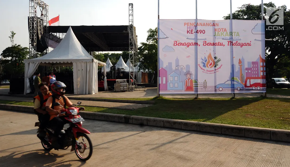 Warga melintasi area Konser Kebangkitan Nasional dan Pencanangan HUT Jakarta ke 490 di Taman Kota Waduk Pluit, Jakarta, Jumat (19/5). HUT Jakarta ke 490 mengambil tema Beragam, Bersatu dan Melayani. (Liputan6.com/Helmi Fithriansyah)
