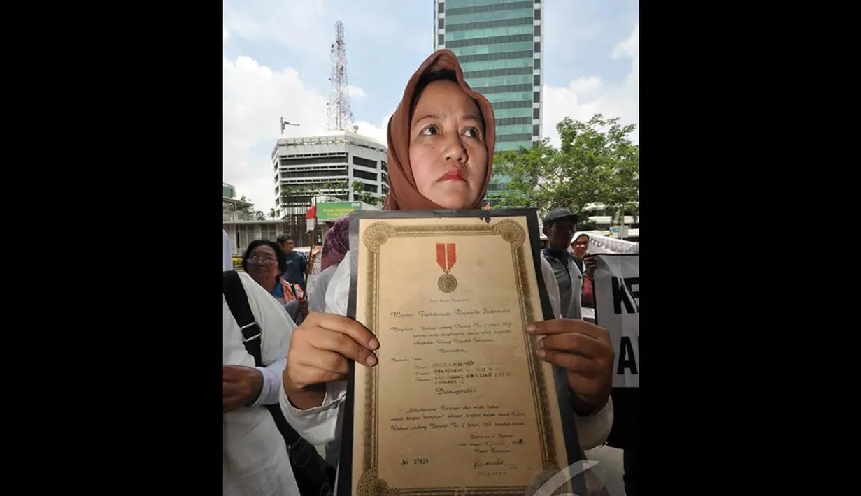 Seorang wanita dari keluarga veteran membawa piagam bintang gerilya saat melakukan unjuk rasa di depan Gedung KPK, Jakarta, Kamis (18/12/2014). (Liputan6.com/Miftahul Hayat)
