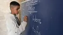 Seorang anak laki-laki Palestina berdiri di depan papan tulis saat pelajaran Bahasa Inggris di sekolah bersejarah "Al-Kamaliya al-Othmanya" di Kota Tua Gaza yang menjadi bagian dari inisiatif sukarelawan yang diorganisir oleh para guru pengungsi, di Kota Gaza pada 2 November 2025. Seiring berlakunya gencatan senjata, berbagai upaya mulai dilakukan secara bertahap untuk melanjutkan proses pembelajaran. (Omar AL-QATTAA/AFP)