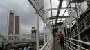 Warga melintasi Jembatan Penyeberangan Orang (JPO) yang rusak di kawasan Dukuh Atas, Jakarta, Rabu (12/12). Rusaknya JPO membahayakan pejalan kaki yang melinatas karena jembatan menjadi licin saat hujan. (Liputan6.com/JohanTallo)