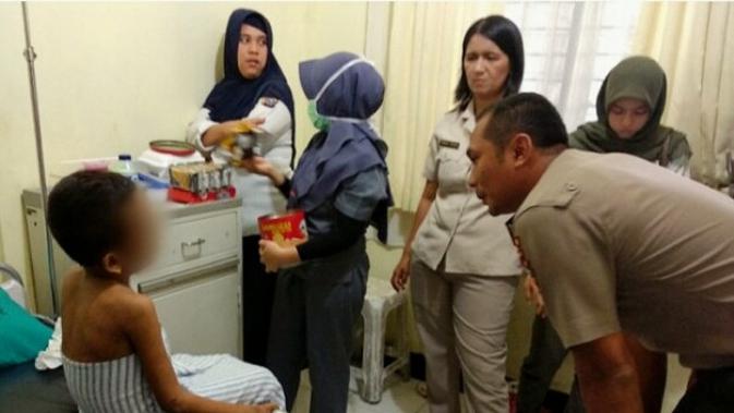 Polisi mengajak bocah korban penganiayaan berkomunikasi di ruang isolasi RS Bhayangkara Polda Riau. (Liputan6.com/ M Syukur)