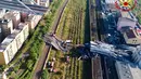 Tim penyelamat berada di antara puing-puing jembatan jalan raya Morandi yang ambruk di Genoa, Italia, Selasa (14/8). Hanya 100 meter dari total satu kilometer panjang jembatan tersebut yang dilaporkan ambruk. (Vigili Del Fuoco via AP)