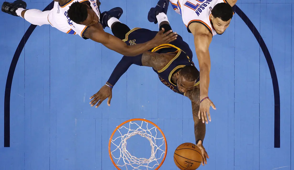 Pebasket Cleveland Cavaliers, LeBron James, menghindari block pebasket Oklahoma City Thunder, Jerami Grant dan Andre Roberson. Ini merupakan kekalahan ke-16 bagi Cavs pada musim ini. (EPA/Larry W. Smith)