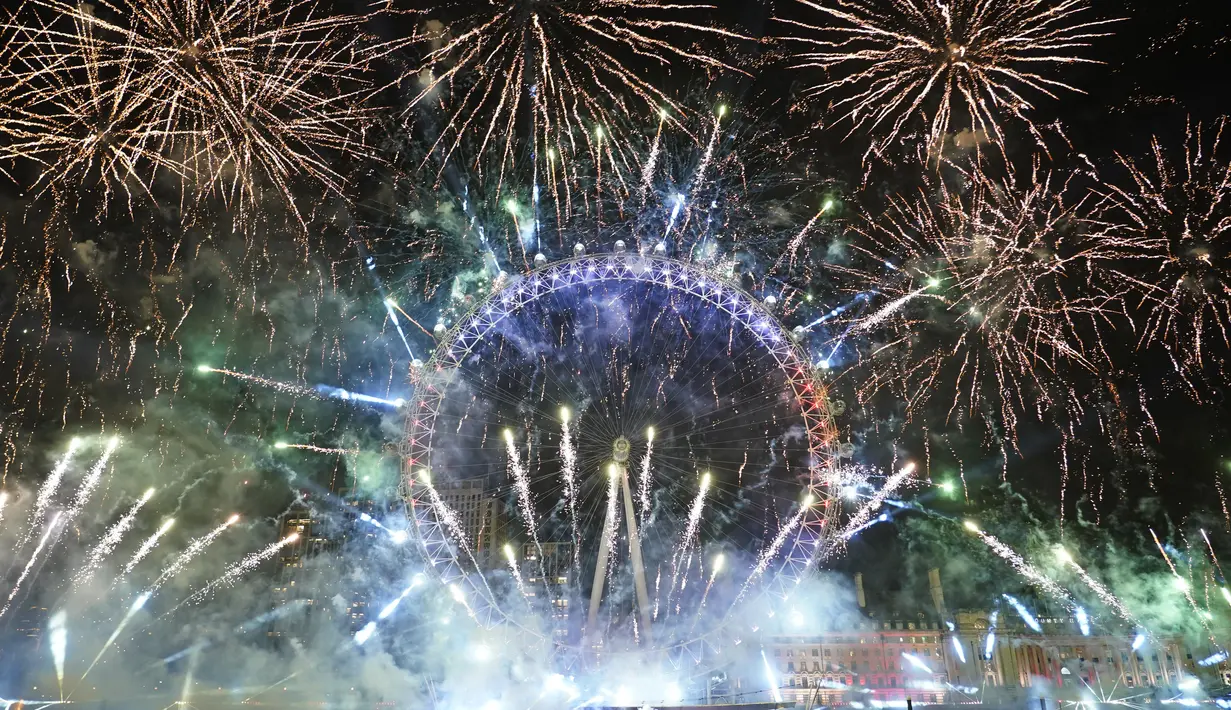 Kembang api menerangi langit di atas London Eye di pusat kota London untuk merayakan Tahun Baru pada Minggu (1/1/2022). Malam pergantian tahun identik dengan pesta kembang api. (AP Photo/Alberto Pezzali)