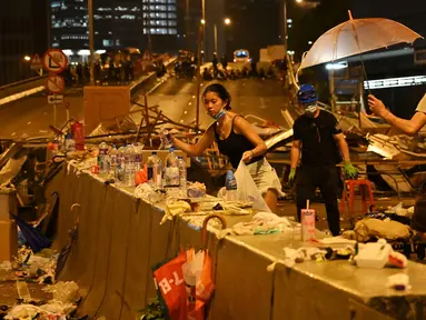 Demonstran membersihkan sampah setelah aksi menolak RUU ekstradisi di Hong Kong (12/6/2019). Aksi tersebut berujung bentrok antara polisi dan warga dimana puluhan ribu orang memblokir jalan-jalan di kota tersebut. (AFP Photo/Hector Retamal)