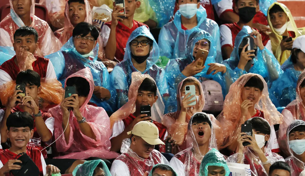 Sejumlah fans Liverpool menggunakan jas hujan saat menyaksikan sesi latihan The Reds di Stadion Rajamangala. (AFP/Jack Taylor)