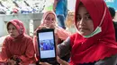 Keluarga korban kapal tenggelam KM Sinar Bangun menunjukkan foto anggota keluarganya di pelabuhan feri Danau Toba, Sumatera Utara, Rabu (20/6) . Foto keluarga yang dilaporkan hilang itu untuk mempermudah proses pendataan. (AFP PHOTO/IVAN DAMANIK)