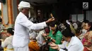 Pemuka agama Hindu memberikan air suci selama prosesi upacara mecaru di Pura Tribhuana Agung Sukmajaya Depok, Jawa Barat, Rabu (6/3). Upacara Mecaru dilaksanakan sebelum Hari Raya Nyepi pada waktu Sasih Kesanga. (Liputan6.com/Herman Zakharia)